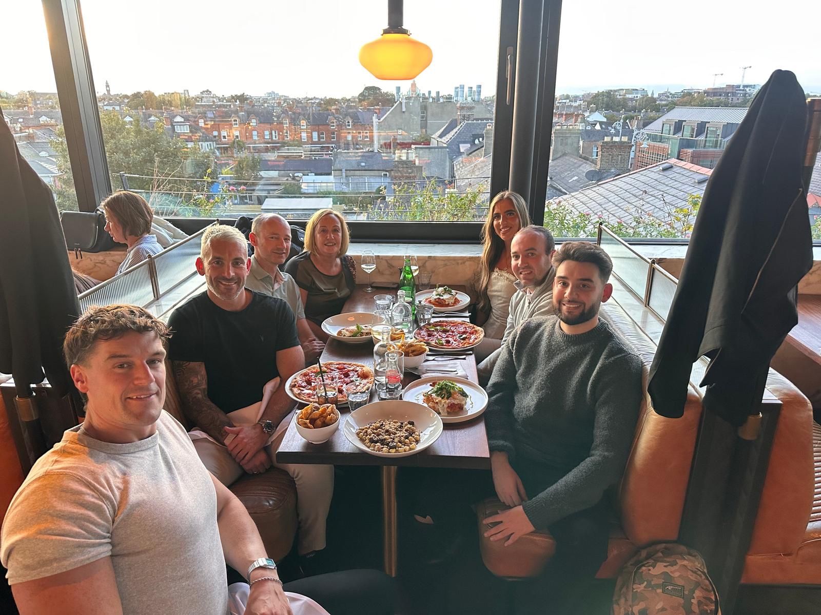 The Inspire Medical team round a table at a restaurant overlooking the city rooftops